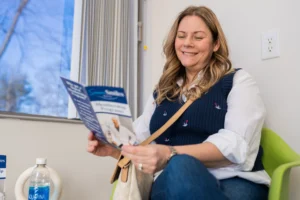 A blonde woman smiling and reading a Sincere Smiles pamphlet.