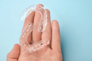 a hand holding an invisalign pair with a light blue background